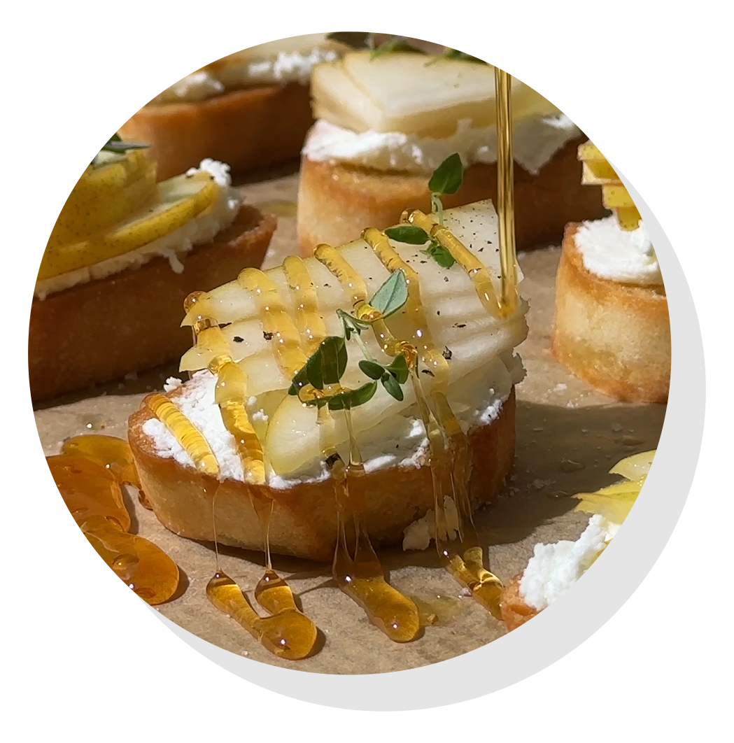 Honey being drizzled over pear crostini.