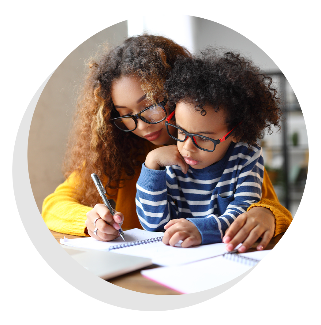 Woman helping a child with a writing in notebook.