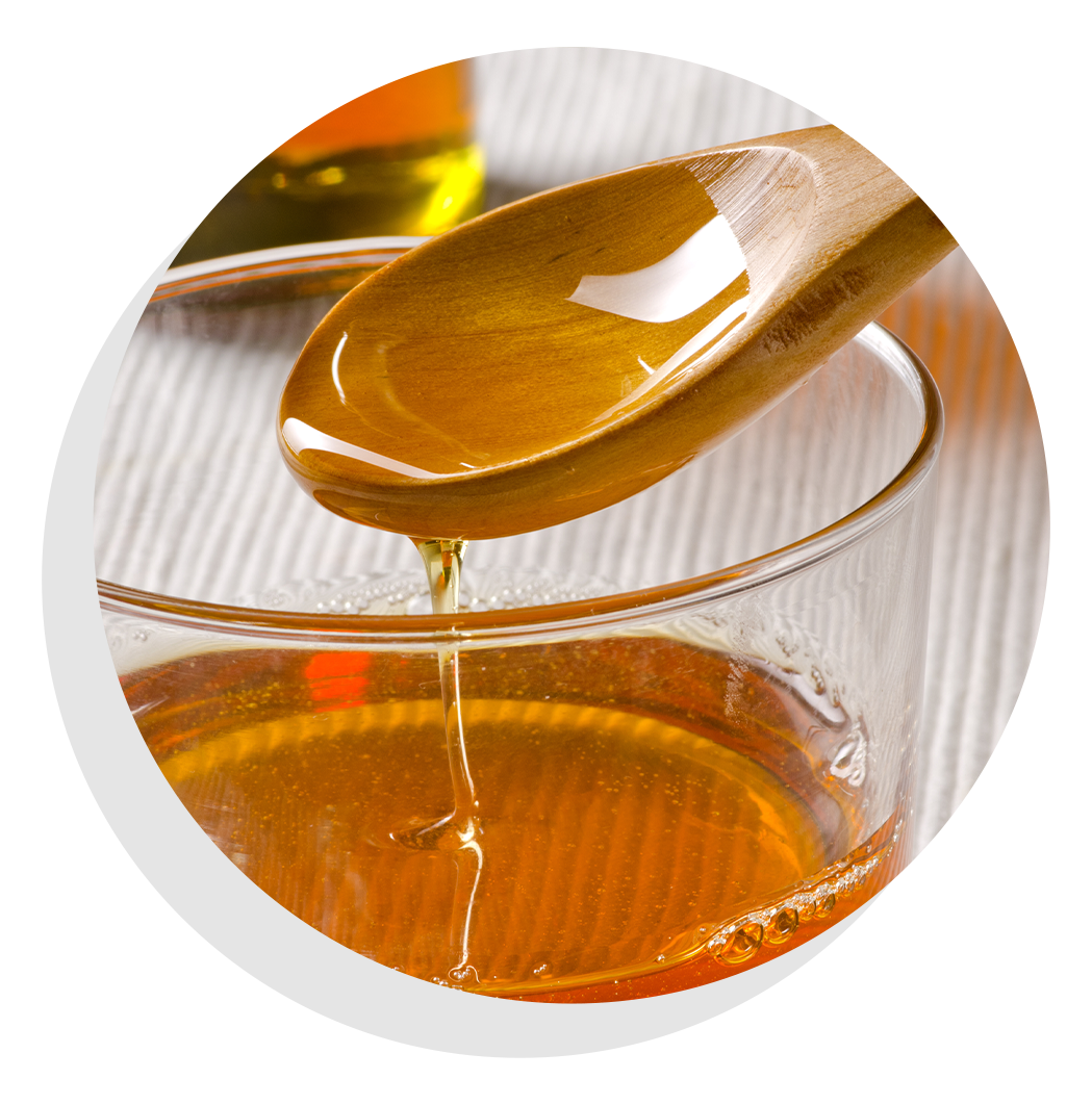 Wooden spoon dipped into clear bowl of agave.