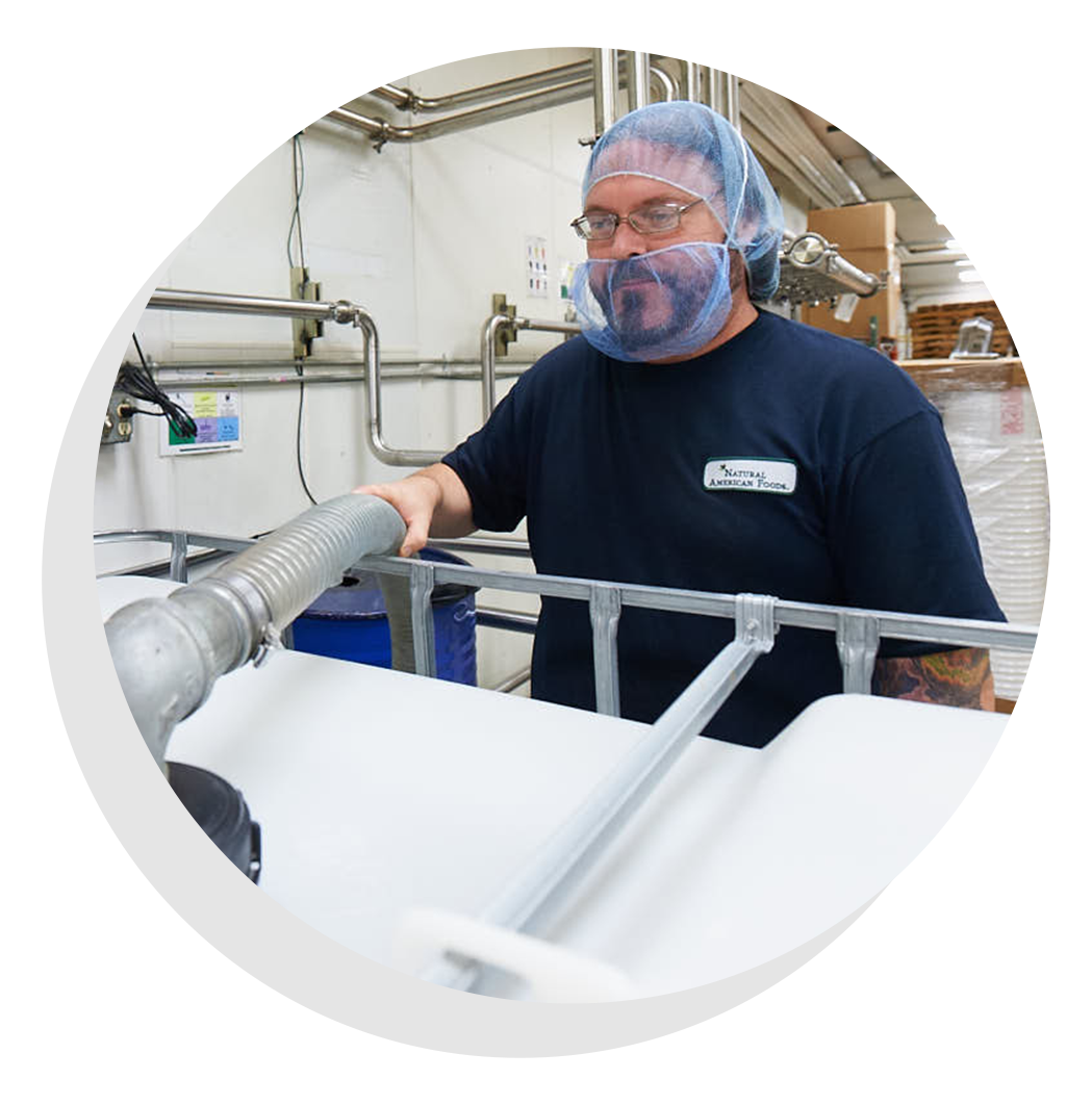 Factory worker in a hairnet standing inside facility.