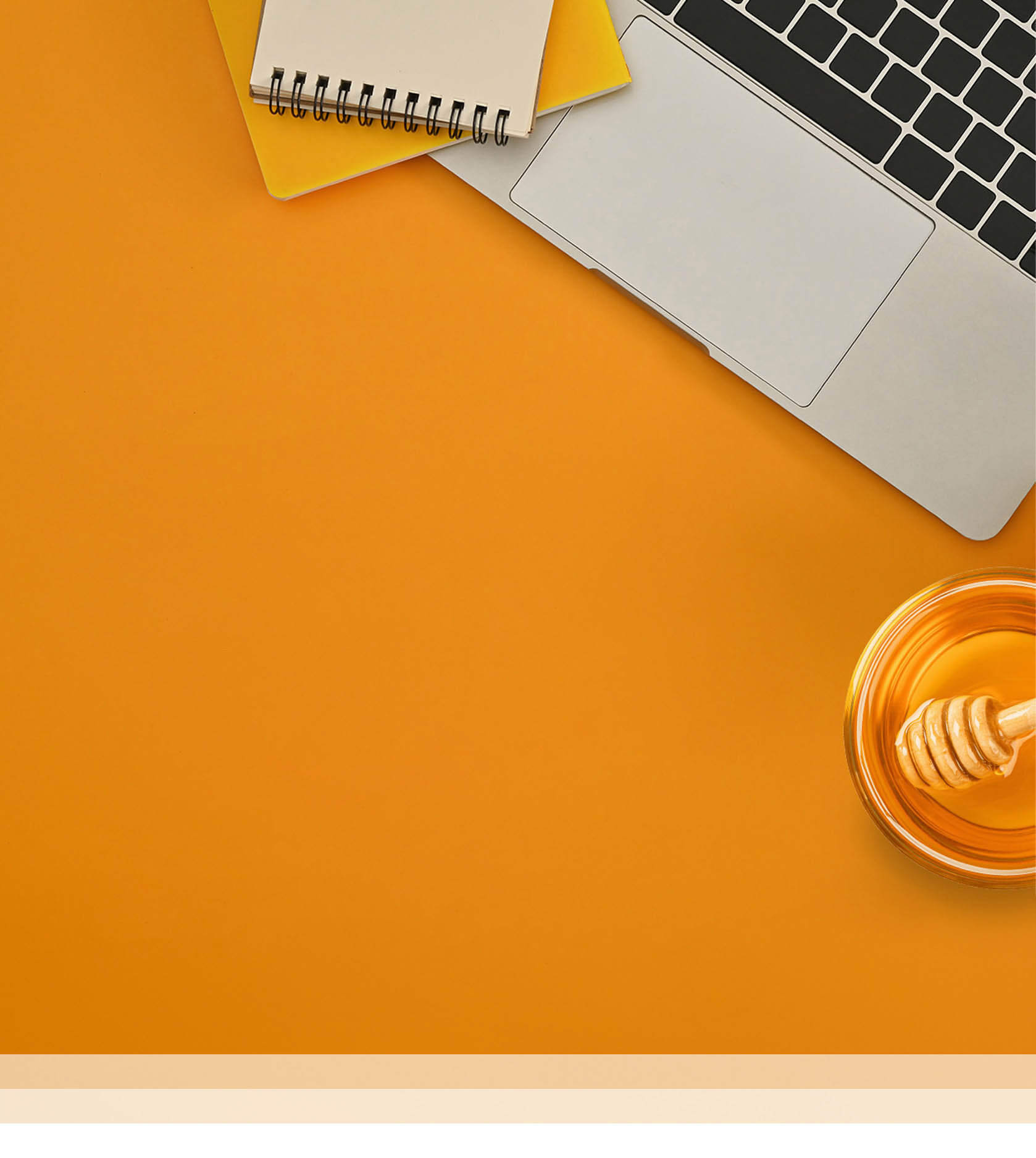 Workspace with laptop, notebook, and honey dipper, on yellow background